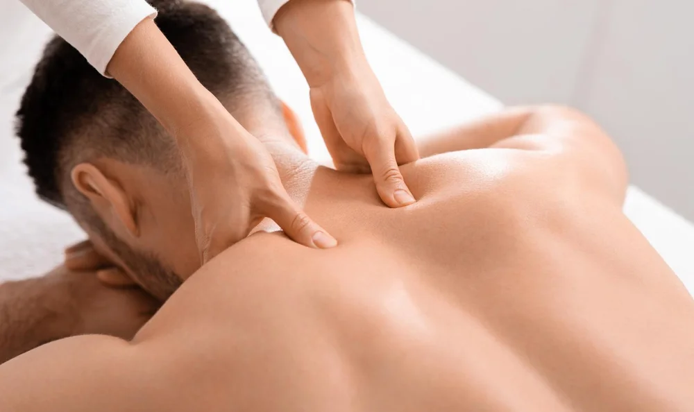 Therapist applying firm pressure to a client's shoulders and upper back